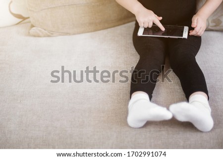 Child watching online cartoons, leafing and swipe. Distance learning, online education for kids. Little girl studying at home in front of the smartphone. Quarantine at home