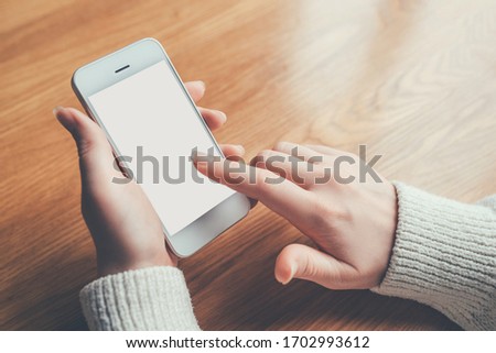 Woman's hands holding phone with white screen. Copy space for your text message.