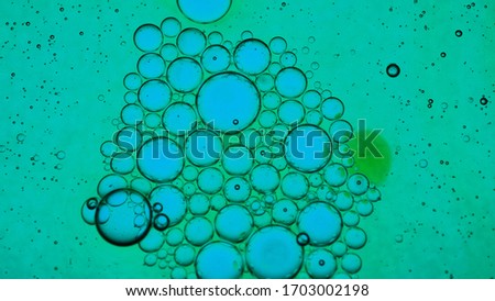 Mixing water and oil, beautiful colors. Green light. Close-up. Abstract macro background. Water and oil bubbles. Abstract light illumination