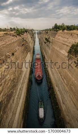 Corinth Canal connection in greece, with a big boat freighter cargo ship tug on a river conneting the Gulf of Corinth with the Saronic Gulf in the Aegean Sea Royalty-Free Stock Photo #1703004673