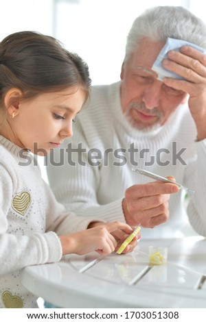 Granddaughter giving medicine to her grandfather in room at home