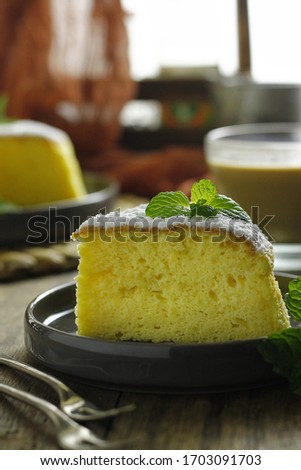 slice of cheese cake on a gray plate with a sprinkling of refined sugar. on a wooden background and dark moody photography