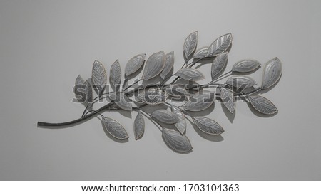 Silver and black leaf decoration on a grey wall