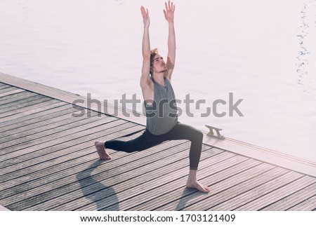 Young sportsman performing articular movements of yoga in an urban area of the city. Royalty-Free Stock Photo #1703121409