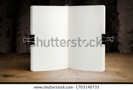 Notebook mockup on a background of wooden table and drapery