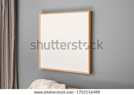 Interior decoration, empty wooden square frame, poster white canvas mock up on a gray wall, living room template angle view