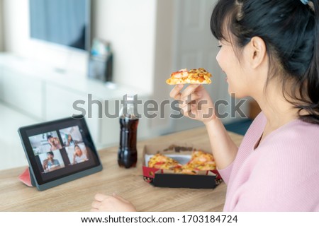 Asian woman virtual happy hour meeting party and eating food online together with her friend in video conference with digital tablet for a online meeting in video call for social distancing  Royalty-Free Stock Photo #1703184724