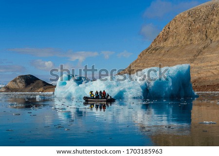 Landscape with iceberg in Greenland at summer time. Sunny weather. Inflatable boat with tourists.