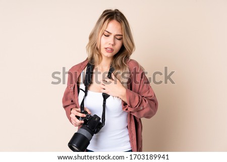 Young photographer girl over isolated background having a pain in the heart