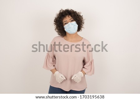 Young beautiful woman wearing face mask over isolated background happy face smiling with hands in pockets looking at the camera. Positive person.