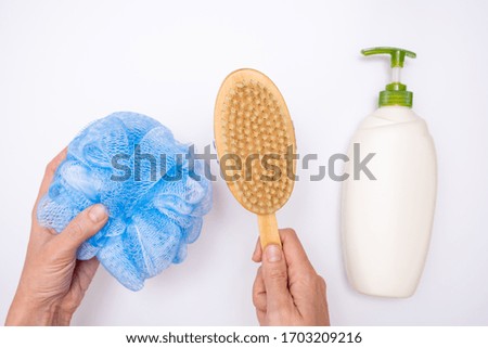 Female woman hands holding shower accessories, sponge and shower gel, body wash and scrubbing, peeling wooden brush on white background.