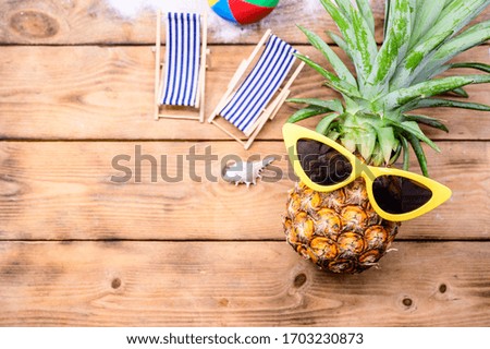 Pineapple with sunglasses on wood background. Creative minimal summer holiday concept with miniature toy.