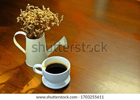 A cup of hot black coffee, hot Americano coffee with morning sunlight on the wooden table.