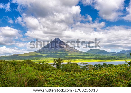 Amazing view of beautiful nature of Costa Rica with smoking volcano Arenal background. Panorama of volcano Arenal reflected on wonderful picturesque lake, La Fortuna, Costa Rica. Central America. Royalty-Free Stock Photo #1703256913
