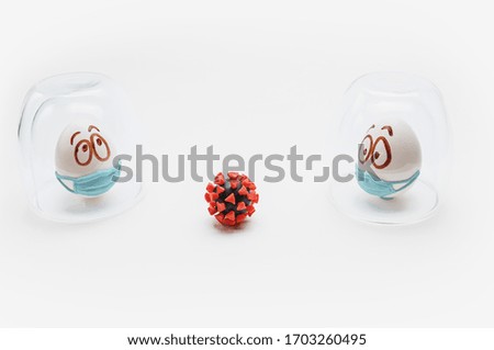 Two easter eggs in medical masks are isolated under glass caps on a white background with model of coronavirus. The concept of Easter holiday 2020 in connection with the corona virus quarantine and