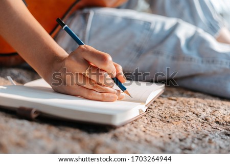 songwriter create and writing notes,lyrics in the book on stone at parks. Royalty-Free Stock Photo #1703264944