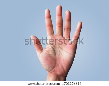 Close-up of hand with point ache on palm and numb fingers joint pain isolated on blue background.