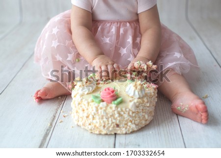One year old baby celebrates birthday. Photo zone for smash cake. Cute dress in pink color.