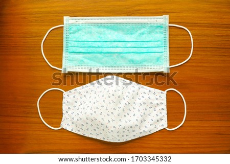 Top view of green surgical medical face mask for doctor, nurse or patient and DIY fabric cotton mask for general people.  Royalty-Free Stock Photo #1703345332