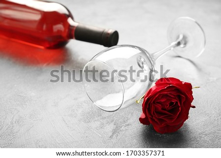 Bottle of wine, glass and rose on grey background