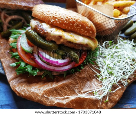 Hamburger with​ cheese​ and​ French fried, salad, picked vegetables 