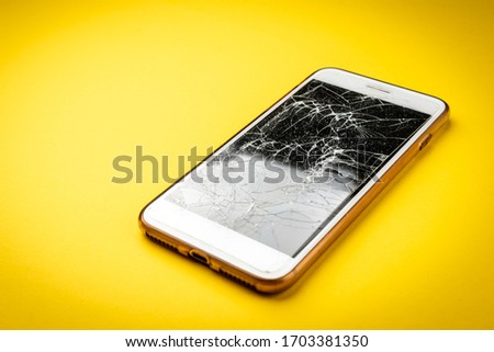 Broken glass screen smartphone on yellow background.