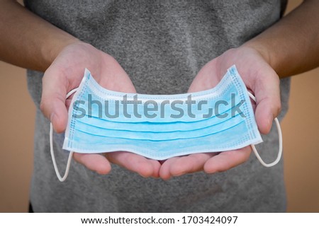 Face mask was held in human's hands. A man with a doctor mask in his hand. Protection mask for against the corona virus, covid-19. A man receive a face mask from another. Royalty-Free Stock Photo #1703424097