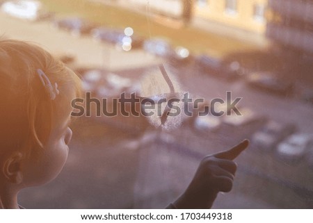 Girl looks lonely through window by putting her hands on window sill