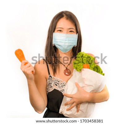 food groceries shooping during covid-19 virus quarantine and home lockdown - young beautiful happy and positive Asian Chinese woman in face mask carrying bag with vegetables smiling