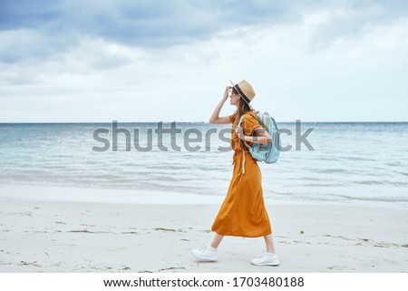 Traveling woman backpack orange sundress sand island