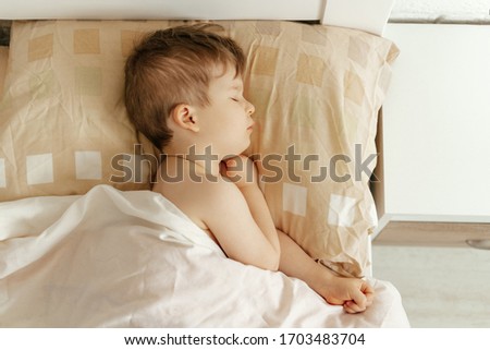 Little Boy Sleeping in Comfortable Bed Top View. Child with Closed Eyes Lying on Pillow and Covered Blanket. Caucasian Kid Dream and Rest. Bedtime Early Morning Horizontal Photography