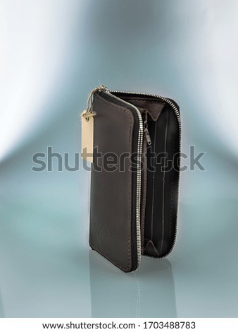 black leather wallet with iron zipper on a light background, gray gradients