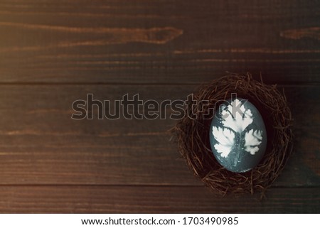 Painted blue eggs with printed picture of parsley in nest on wooden table. Easter decoration concept. Top view rustic background