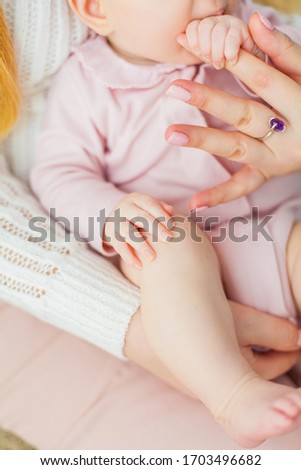 Beautiful young mother holds the hands of her little daughter. Baby. Newborn.