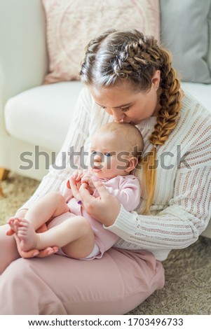 A beautiful young mother holds in her arms a small pretty blue-eyed 2-month-old daughter. Newborn. Baby.