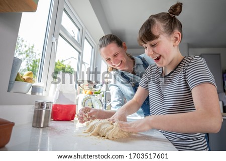 Mother And Daughter Having Fun In Kitchen At Making Dough For Home Baked Bread Together Royalty-Free Stock Photo #1703517601