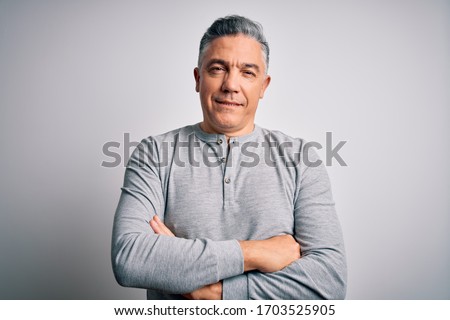 Middle age handsome grey-haired man wearing casual t-shirt over white background happy face smiling with crossed arms looking at the camera. Positive person.