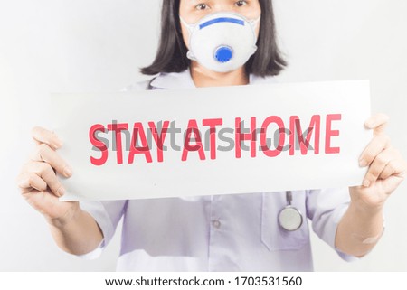 Asian doctor wear medical masks, holding paper with text STAY AT HOME. stay at home policy campaign to control COVID-19 Coronavirus outbreak situation