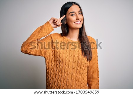 Young beautiful brunette woman wearing casual sweater over isolated white background Smiling pointing to head with one finger, great idea or thought, good memory