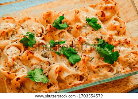 cooking at home Italian cuisine. baked large meat stuffed pasta in glass pan on wooden Board.