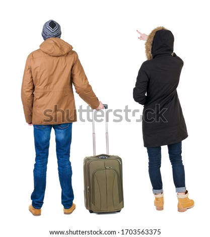 young couple in winter jacket traveling with suitcas. Back view. Rear view people collection. backside view of person. Isolated over white background.
