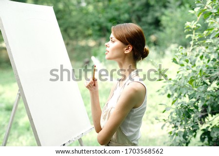 young easel woman paints outdoors