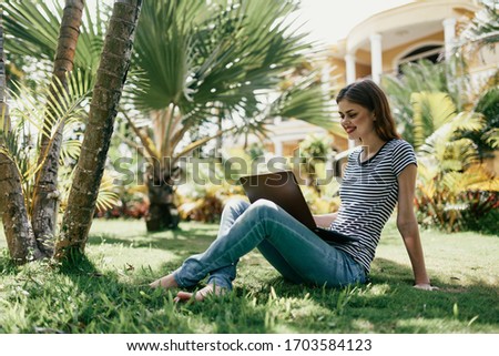 young woman with laptop in t-shirt outdoors