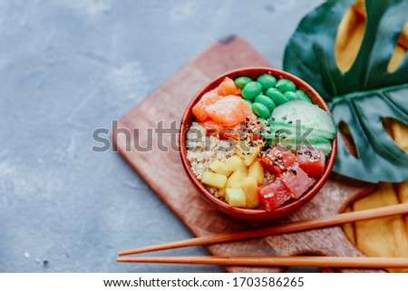 Hawaiian salmon poke bowl with rice, avocado, cucumber, carrot, chukka and sesame seeds on a blue background. top view