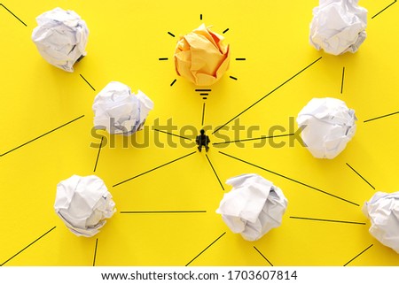A concept image of a man looking at crumpled paper as light bulb and finding the right idea
