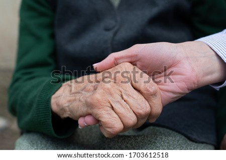 Close up picture of caregiver holding senior woman's wrinkled hands 