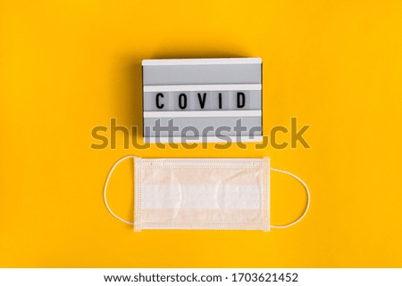 Surgical mask with text stay COVID on white lightbox isolated on yellow background. Stop virus. Coronavirus pandemic. Concept Of Air pollution, flat lay banner