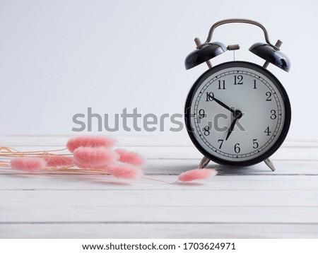 Alarm clock and dry grass decoration on white wooden table with copy space.