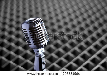 Closeup of chrome retro condenser microphone on acoustic foam panel background