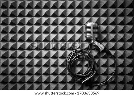 Retro microphone with cable lying on acoustic foam panel background, flat lay